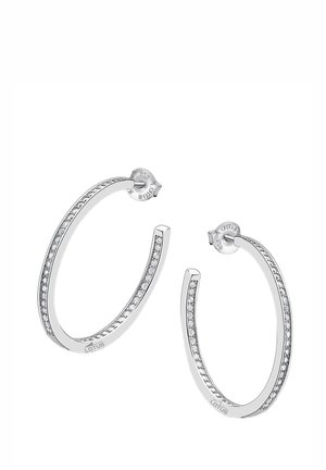 Boucles d'oreilles en argent avec un design lisse et courbé, ornées de petites pierres précieuses transparentes incrustées le long d'un bord et d'une fermeture à tige.