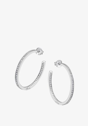 Boucles d'oreilles en argent avec un design lisse et courbé, ornées de petites pierres précieuses transparentes incrustées le long d'un bord et d'une fermeture à tige.