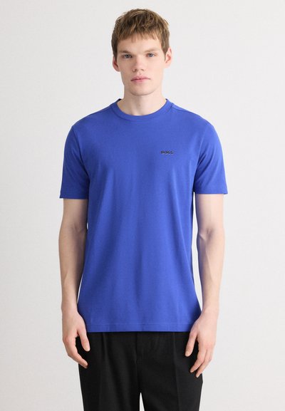 T-shirt bleu à manches courtes en coton doux, avec un col rond et un petit logo noir sur la poitrine.