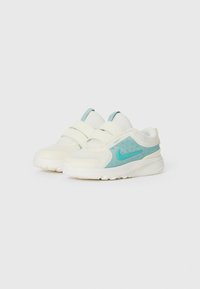 Des baskets Nike blanches et bleu clair pour enfants avec des brides Velcro et des semelles rembourrées, présentées côte à côte sur un fond blanc.