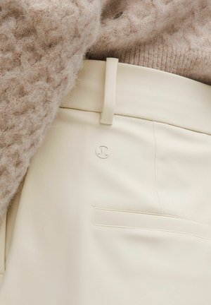 Hose in cremefarben aus glattem Stoff mit schmaler Passform. Verfügt über ein dezentes Logo, eine Seitentasche und ein flaches Taillenbund-Design.