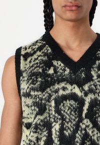 Gehaakte mouwloze trui met een zwart en lichtgroen patroon, V-halsontwerp, gestructureerde stof en geribbelde rand.