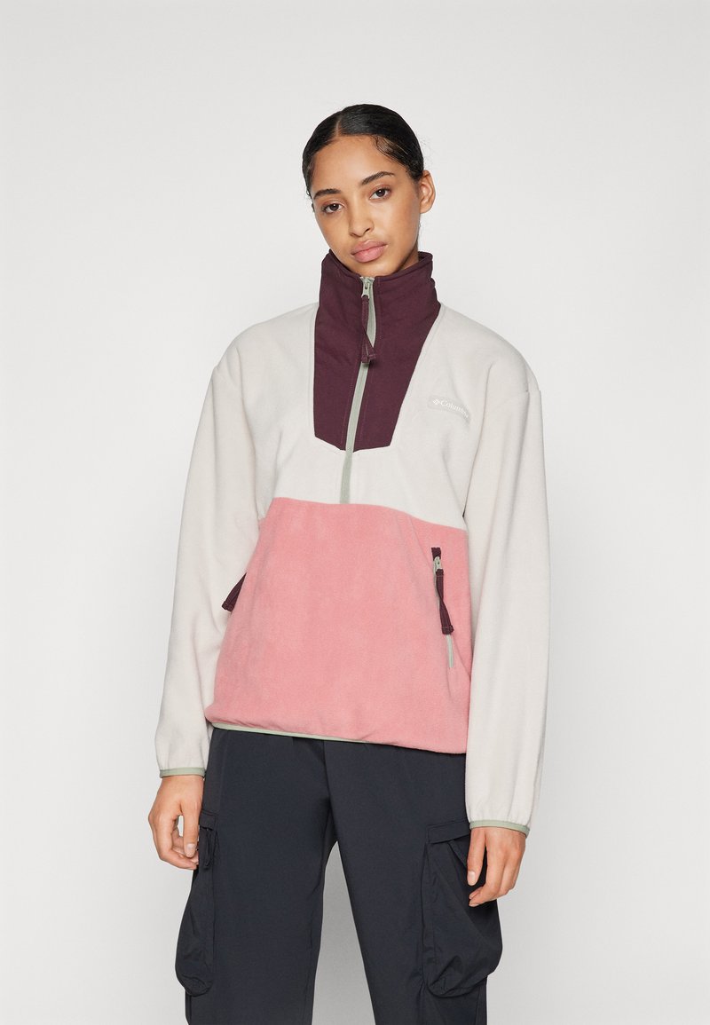 Fleece genser i krem, rosa og burgunder. Har høy krage, glidelås foran og sidelommer med glidelås. Myk tekstur.