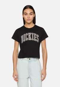 Schwarzes, kurzes Baumwoll-T-Shirt mit dem Wort "DICKIES" in großen, gewölbten weißen Buchstaben mit einem leichten Umriss. Klassischer Rundhalsausschnitt.