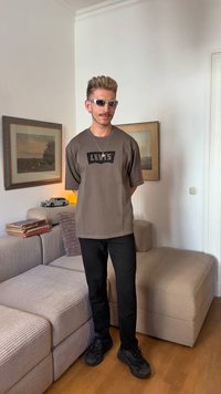 Camiseta corta de Levi's en color marrón con logo negro, combinada con pantalones negros y zapatillas oscuras. Unas gafas de sol modernas completan el look.