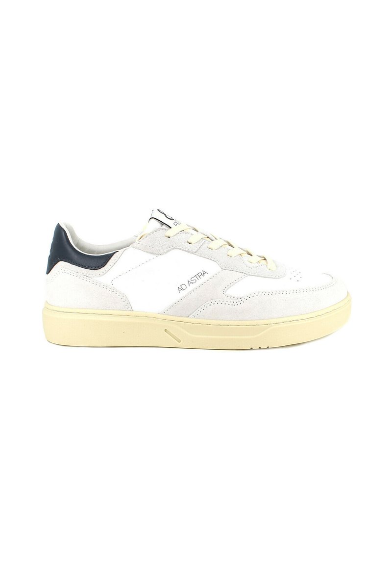 Sneakers in suede bianco con un accento blu navy sul tallone, punta tonda e suola gialla chiara. Presentano perforazioni sulla punta e un marchio sul lato.