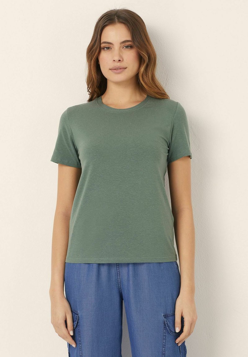 T-shirt verde a maniche corte con colletto tondo, realizzato in tessuto morbido con una leggera trama, abbinato a pantaloni cargo blu.
