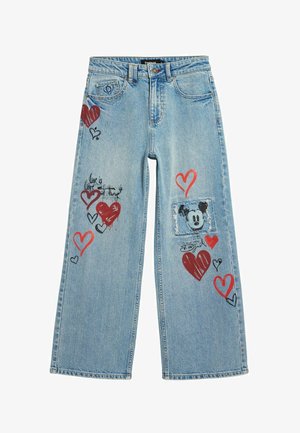 Jean en denim bleu clair avec des motifs de cœurs rouges et noirs, une écusson Mickey Mouse usé sur la jambe droite, et du texte manuscrit sur la jambe gauche.