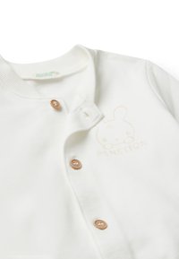 Bílé bavlněné kardigan s kulatým výstřihem, dřevěnými knoflíky a vyraženým designem králíka se slovem "BENETTON".