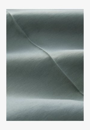 Light blue fabric showcasing a smooth, soft texture with gentle folds and subtle sheen, allowing for a dynamic play of light across the surface.