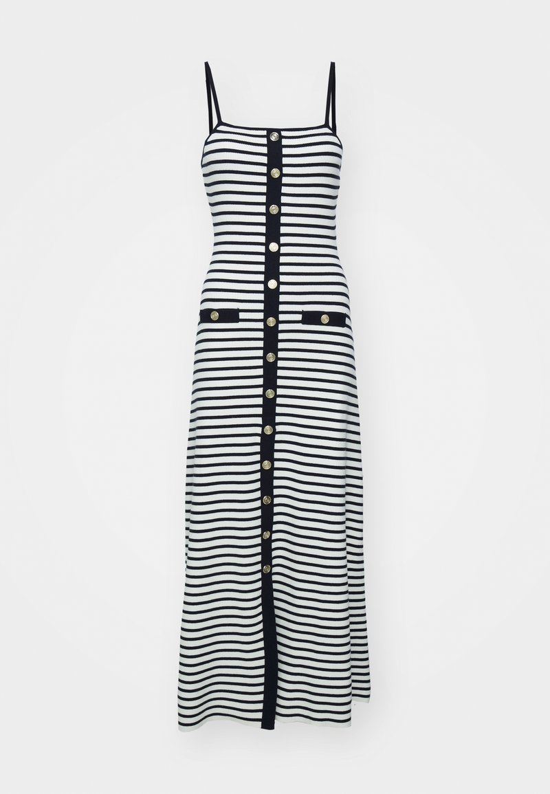 Robe midi rayée en noir et blanc avec des bretelles fines, des boutons dorés sur le devant et deux poches avant bordées de noir.