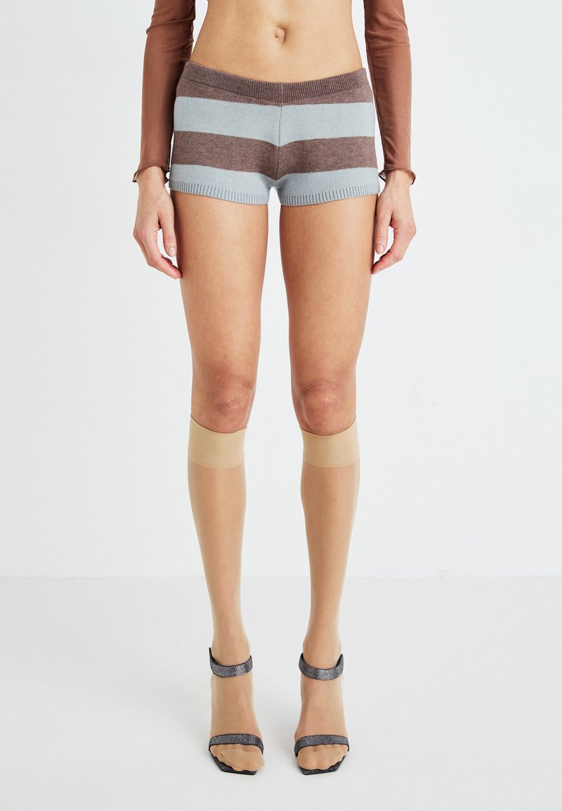 Shorts a righe in maglia azzurro chiaro e marrone con vita a costine, abbinati a calze sopra il ginocchio color nude e sandali trasparenti con tacco a fascia.