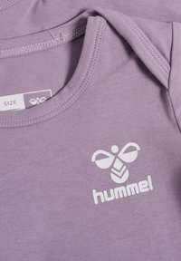 Lila bomullströja med korta ärmar, med en vit "hummel"-logotyp och bi-motiv. Slät textur med ribbat halsband.