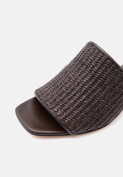 Σκούρο καφέ σανδάλι σαγιονάρα με φαρδιά λουρί υφαντής υφής και τετράγωνο ανοιχτό σχέδιο δακτύλων σε λευκό φόντο.