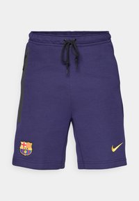 Lila Nike rövidnadrág fekete húzózsinórral, oldalsó cipzáras zsebekkel és hímzett Barcelona logóval. Simább anyag és laza fazon.