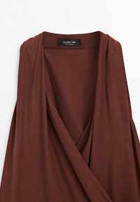 Hnědý bezrukávový oděv ve stylu zábalu z měkké látky s černou štítkem Massimo Dutti vyroben v Maroku.