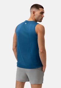 Top atletico blu in tessuto leggero, con collo alto e design senza maniche. Il retro presenta una leggera lavorazione delle cuciture.