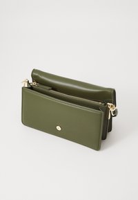 Portafoglio in pelle verde oliva con ferramenta dorata, chiusura a zip e design strutturato. Presenta un esterno liscio e un dettaglio del logo minimalista.