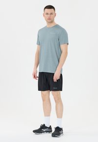 Vaaleansininen lyhythihainen t-paita, mustat urheilushortsit, valkoiset urheilusukat ja mustat juoksukengät, joissa on teksturoitu pinta ja näkyviä yksityiskohtia.