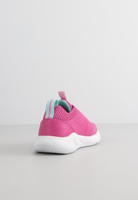 Zapatilla rosa con parte superior de tejido texturizado, suela de goma blanca y lengüeta trasera azul clara. Presenta un diseño sin cordones y sin lazos visibles.