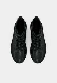 Sorte skinn ankleboots med en glatt overflate, rund tå og sølvfarget detaljer. Har snøring, polstret krage og et bånd på baksiden.