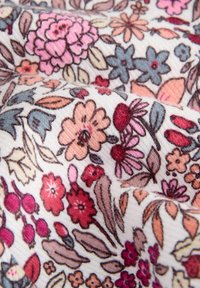 Bloemstof met een witte achtergrond, met complexe patronen van roze, rode en blauwe bloemen, met fijne details en een zachte textuur.