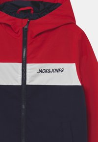 Červená, bílá a navy barevně blokovaná bunda se zipem vpředu, kapucí a logem "JACK&JONES" na hrudi. Hladká tkanina se sportovním designem.