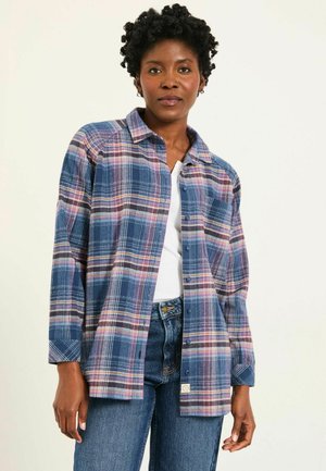 Plaid button-up shirt in blue, pink, and white tones; features a collar, long sleeves, and a relaxed fit. Worn over a white top.