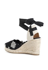 Espadrille con zeppa in bianco e nero, con tomaia in tessuto testurizzato, suola avvolta in juta e laccio alla caviglia in nero. Design con punta aperta.