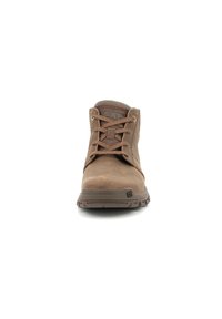 Botas de tobillo de cuero marrón con parte superior texturizada, punta redonda y diseño con cordones. La suela de goma cuenta con ranuras de tracción. Logo de CAT visible.