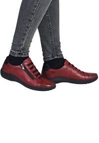 Baskets en cuir rouge avec une finition texturée, dotées d'une fermeture éclair sur le côté, de bandes élastiques noires et d'une semelle en caoutchouc noir flexible.