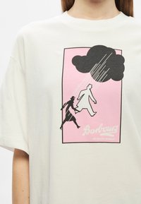 Kreemvalge ülemaahuline t-särk, millel on roosa graafiline disain, mustade kahe figuuri siluetid ja pilv vihmaga.