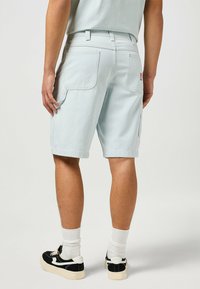 Pantalones cortos a rayas azul claro con un corte relajado, dos bolsillos traseros y un bolsillo lateral tipo cargo. Fabricados en algodón con una textura suave.