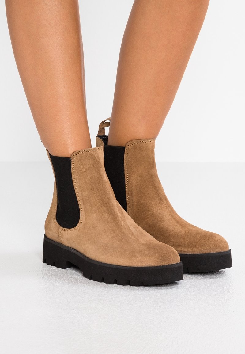 Bottes cheville en daim marron avec panneaux latéraux élastiques noirs et semelles en caoutchouc noir épaisses. Dotées d'une boucle à l'arrière pour un enfilage facile.