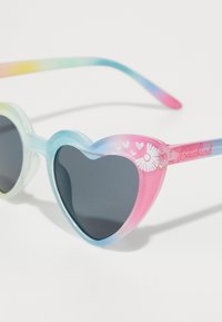 Hartvormige zonnebril met een gradient in pastelkleuren die van blauw naar roze overgaan, met donkere lenzen en bloemaccenten op de pootjes.