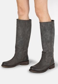 Knöchelhohe graue Lederstiefel mit leicht strukturierter Oberfläche, abgerundeten Zehen und Holzabsätzen. Gestickte Akzente werten das Design auf.