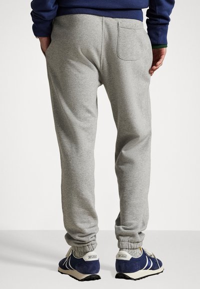 Pantaloni de trening gri, cu o croială ajustată, talie elastică și manșete la glezne. Dispune de un buzunar la spate și o țesătură moale, texturată.