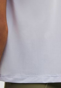 Camiseta deportiva blanca con un tejido texturizado, con dobladillo recto y mangas cortas, combinada con pantalones cortos verdes.