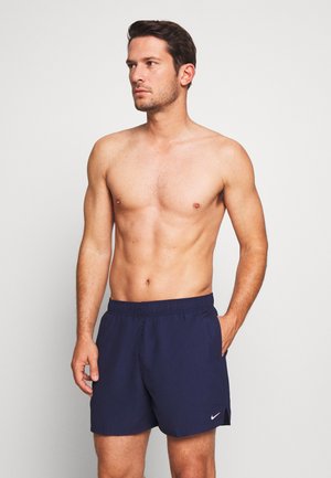 Shorts de bain bleu marine avec une taille élastique, poches latérales et un logo blanc en bas de l'ourlet. Tissu lisse et design jusqu'aux genoux.