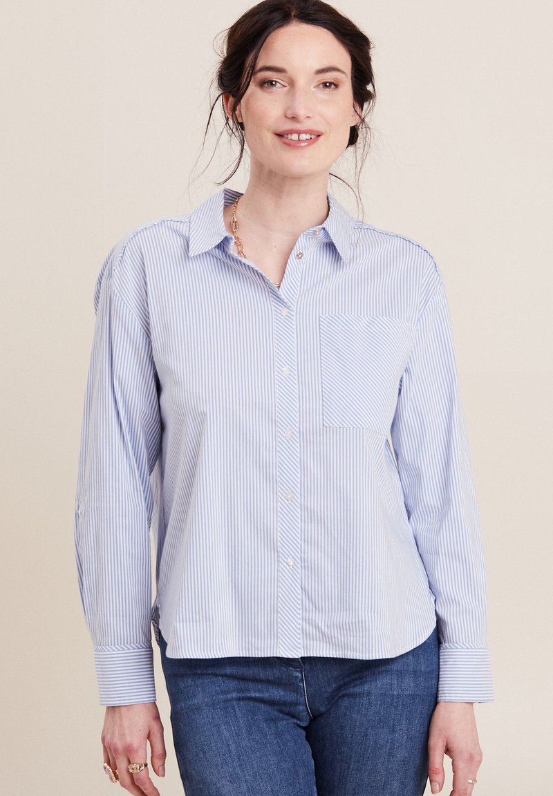 Camicia button-up a righe blu chiaro con colletto, taschino sul petto, maniche lunghe e vestibilità comoda. Indossata con jeans blu scuro.