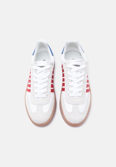 Ζευγάρι λευκών αθλητικών παπουτσιών με κόκκινες ρίγες στο πλάι, μπλε λεπτομέρειες στη φτέρνα, λευκά κορδόνια και σόλες σε χρώμα τσίχλας, φαίνονται από πάνω σε απλό φόντο.