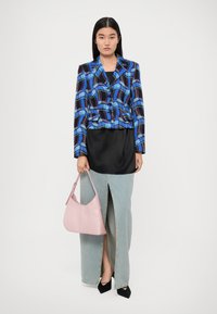 Blazer a motivi blu e neri, top in satin nero, gonna di jeans azzurri con spacco frontale e borsa in pelle rosa. Scarpe nere a punta.