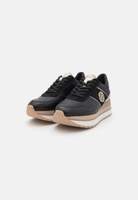 Sneaker nere con accenti in pelle e scamosciato, caratterizzate da una suola spessa beige, una striscia bianca e un dettaglio del logo dorato sul lato.