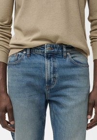 Licht gewassen denim jeans met een rechte pasvorm, voorzien van voorzakken, een knoopsluiting en subtiele vervaging voor textuur.