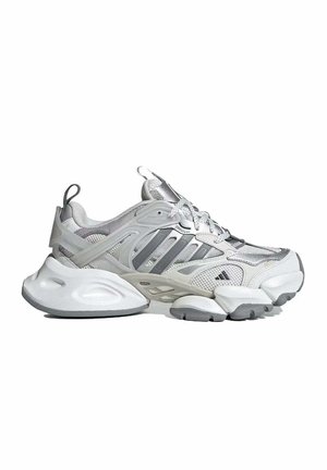 Baskets de sport blanches et argentées avec dessus en mesh et synthétique, semelle épaisse, design à lacets et logo de la marque sur le côté.