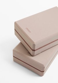 Dva pravokotna darilna škatla v mehkem roza kartonu, z vodoravno rjavo črto. Na vrhu je natisnjen naziv blagovne znamke.