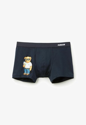 Marineblauwe herenboxers met een beer die een zonnebril draagt, een wit shirt, een spijkerbroek aan heeft en een ijsje vasthoudt, met "IUMAN" op de tailleband.