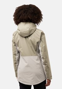 Lichtgewicht, waterdichte jas in beige en grijs. Heeft een goed passende capuchon, lange mouwen en contrasterende panels met een gladde textuur.