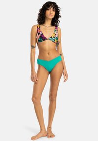 Bikini set featuring a multicolored floral print top with adjustable straps and solid turquoise bottoms, polyester material, smooth texture.