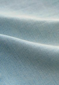 Svijetloplavi denim tkanina s glatkom teksturom, koja se odlikuje finim, suptilnim tkanjem i nježnim padajem, prikazujući nabore i nabori.